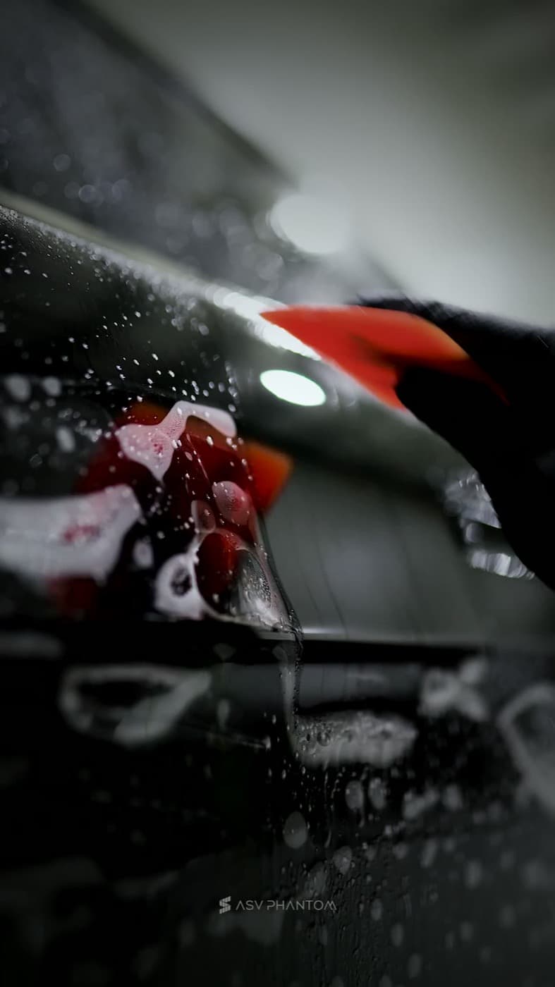 Clear paint protection film on a fender with water droplets during installation
