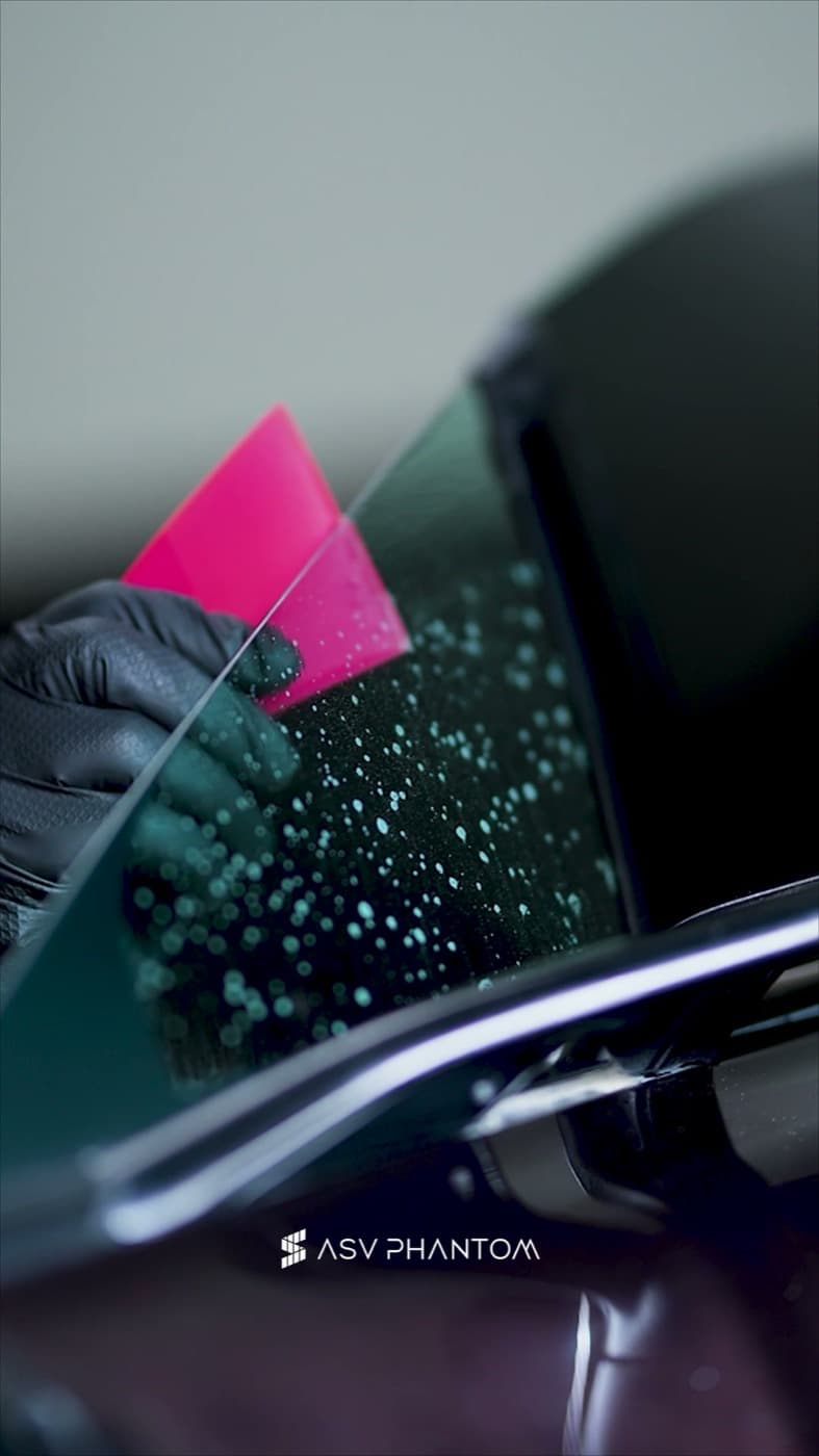 Hand-finishing tint film with a precision squeegee at ASV Phantom Dubai